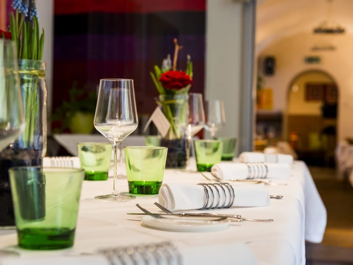 Gedeckter Tisch mit grünen Wassergläsern, Weingläsern, weißem Tischtuch