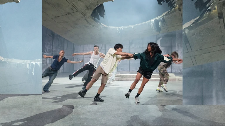 Szenenbild von "Aprés moi, le déluge", choreografiert vom Kollektiv (LA)HORDE und aufgeführt vom Ballet National de Marseille. Zu sehen sind in legérer Straßenkleidung eingekleidete Tänzer:innen, die gleichzeitig - schräg stehend - ein Bein zur Seite in der Luft haben.