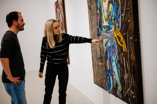 Ein Mann und eine Frau stehen vor einem Kunstwerk in der Kunsthalle Krems und betrachten es intensiv.