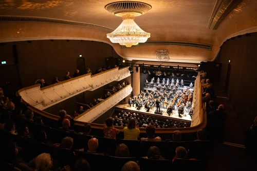 Voller Konzertsaal mit Orchester auf der Bühne