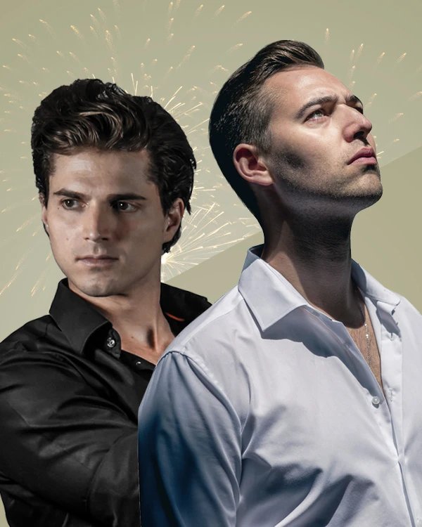 Zwei Personen stehen Rücken an Rücken vor einem Himmel voller Feuerwerk; die linke Person trägt ein schwarzes Shirt und blickt zur Seite, die rechte ein weißes Shirt und schaut nach oben – ein Bild mit starkem Kontrast und festlicher Atmosphäre.