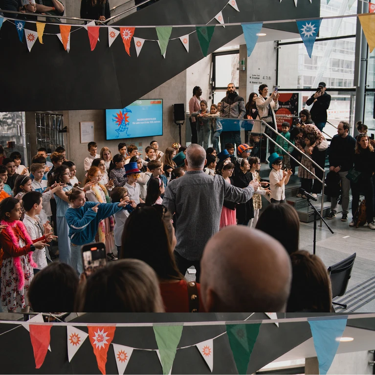 Foto vom BIG BANG Festival mit singenden Kindern im bunt dekorierten Festspielhaus St. Pölten.