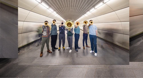 Gruppenfoto vom Bläserensemble "Federspiel", aufgenommen im Schacht einer U-Bahnstation. Die Musiker halten ihre Instrumente nach vorne.