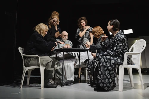 mehrere Menschen sitzen und stehen um einen Tisch