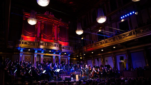 Orchester spielt in einem bunt beleuchteten Konzertsaal