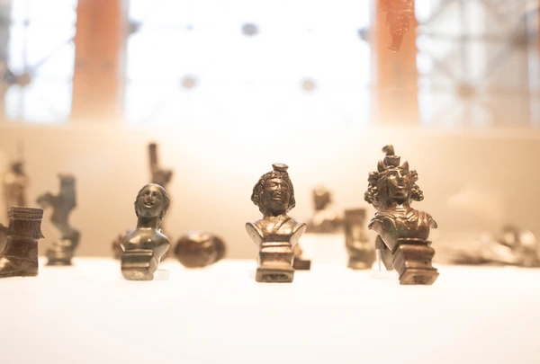 Nahaufnahme von kleinen Figuren in der Vitrine im Obergeschoß des Museum Carnuntinum vor unscharfem Hintergrund.