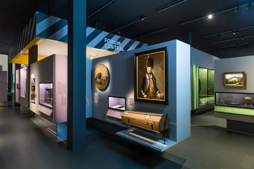 Ausstellungsraum mit Gemälden Vitrinen und Bereichsbeschriftung Forum Central