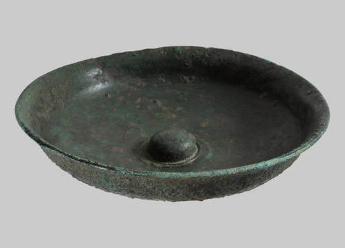 A fully preserved sacrificial bowl with an omphalos set off by a profiled rim. The patera, a handle-less sacrificial bowl typically made of precious materials, was used for liquid offerings.