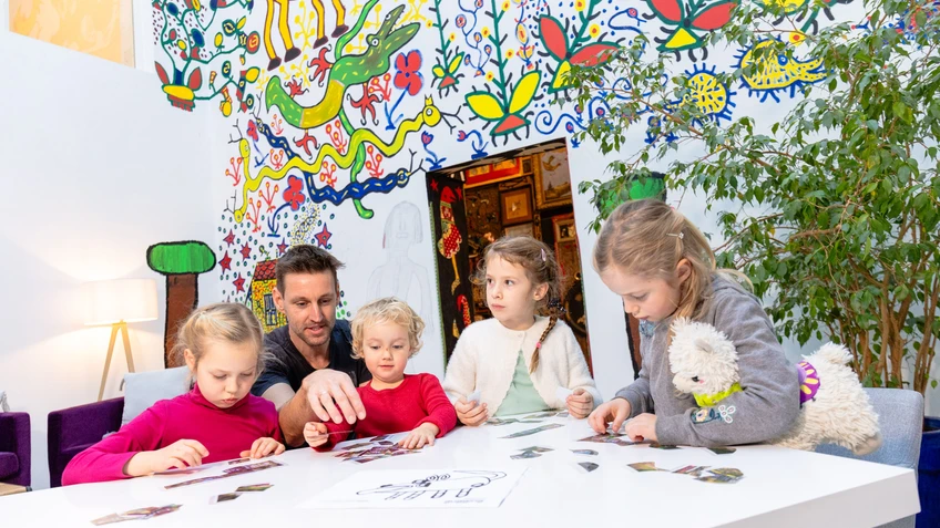Kinder um einen Tisch malen mit Buntstiften Bilder