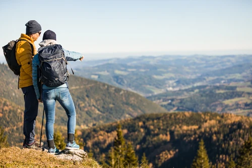 zwei Personen blicken vom Berg ins Tal hinunter