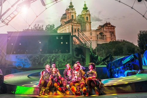 Bunt beleuchtete Theateraufführung im Freien mit Blick auf das Stift Melk in der Abenddämmerung.