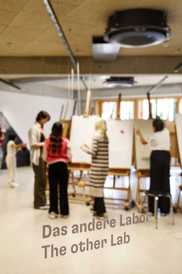 Kinder malen an Staffeleien. Im Vordergrund steht "Das andere Labor/ The other Lab" auf einer Glasscheibe.