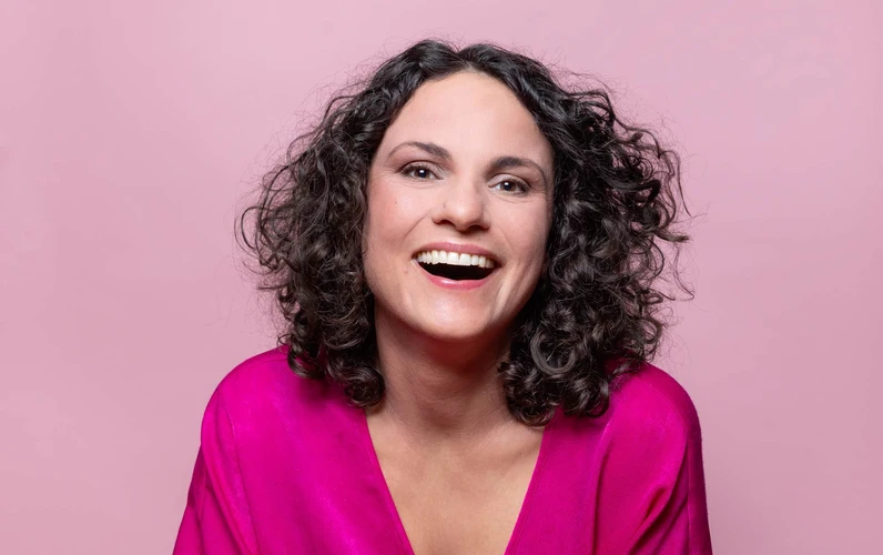 Ein Portraitfoto von Antonia Stabinger, lächelnd vor rosa Hintergrund