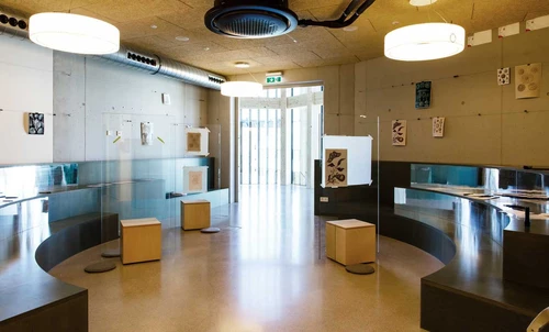 Andreas' Raum in the KinderKunstLabor with semi-circular seating steps along the walls and three elements consisting of wooden blocks with large glass panes for drawing in the middle.