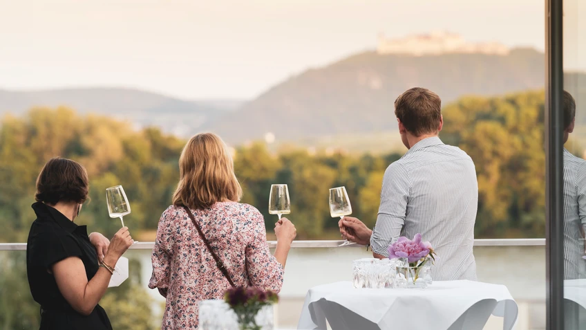 Drei Personen mit Weinglas und mit dem Rücken zur Kamera auf der Landesgalerie Terrasse
