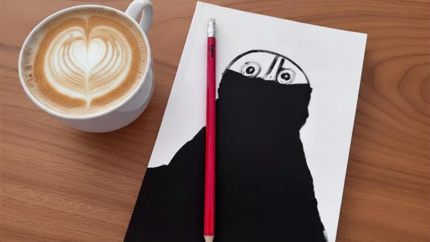 Weiße Kaffeetasse mit Cappuccino auf hellem Holztisch. Daneben liegt ein weißes Blatt Papier mit einer schwarzen, abstrakten Zeichnung, aus der zwei Augen hervortreten. Ein roter Bleistift liegt senkrecht über dem Blatt und teilt die Zeichnung mittig.