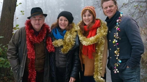 Vier Personen in der Natur, lächeln, mit Weihnachtsgirlanden um die Hälse gewickelt