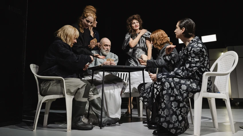 mehrere Menschen sitzen und stehen um einen Tisch