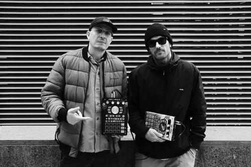 Schwarz-weiß-Foto der beiden DJs Matin.PZ & ZikoTheBaker, beide Teil des Kollektivs GoodBetterFresh bzw. Bakery, ihre Mixing-Technik in Händen haltend.