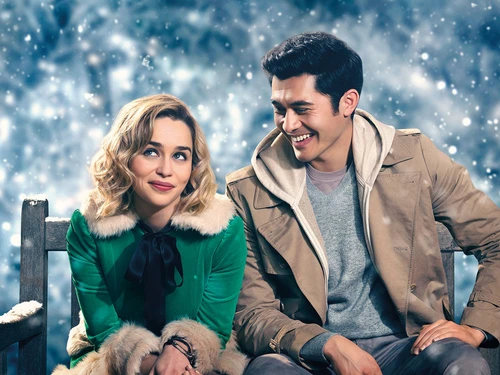 Eine Frau mit blonden Locken in grüner Jacke mit Pelzkragen, daneben ein Mann mit dunklen Haaren in brauner Jacke und Hoodie darunter. Dahinter Schneeflocken am Himmel