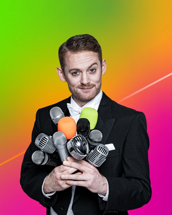 
Mann mit vielen Mikrofonen in der Hand. Hintergrund ist grün, gelb, orange, rosa. Nahaufnahme.