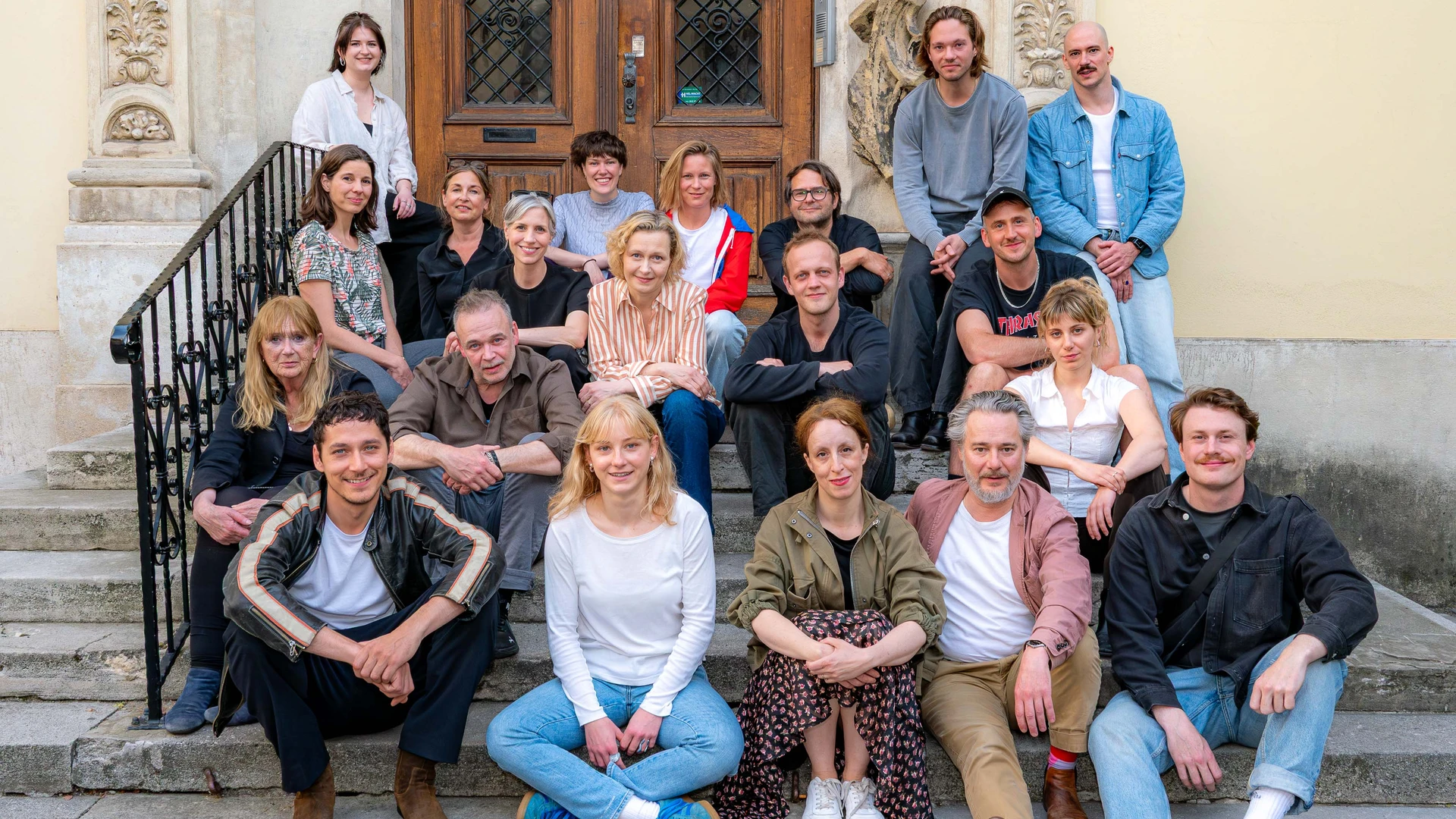 Gruppenbild: gesamtes Ensemble "Krieg und Frieden" auf der Stufe sitzend