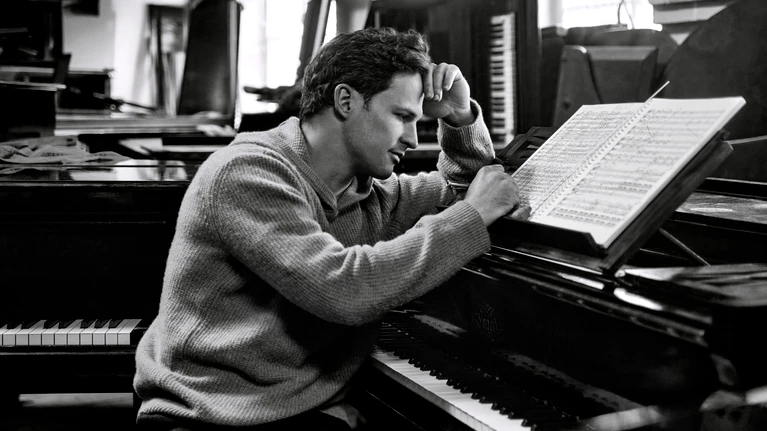 Black and white portrait photograph of conductor Andreas Otensamer at the piano.