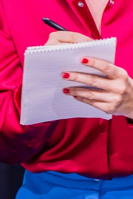 Bildausschnitt auf dem etwas mit Kugelschreiber auf einem Notizblick geschrieben wird.