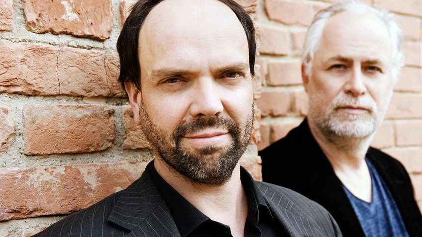 zwei Männer vor roter Ziegelmauer