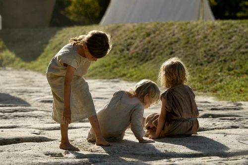 Three children in tunics are playing in the street at the Late Antiquity Festival 2017; the sun is shining