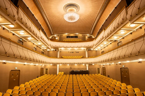 Theatersaal mit gelben Stühlen in hellem Licht mit großem Luster