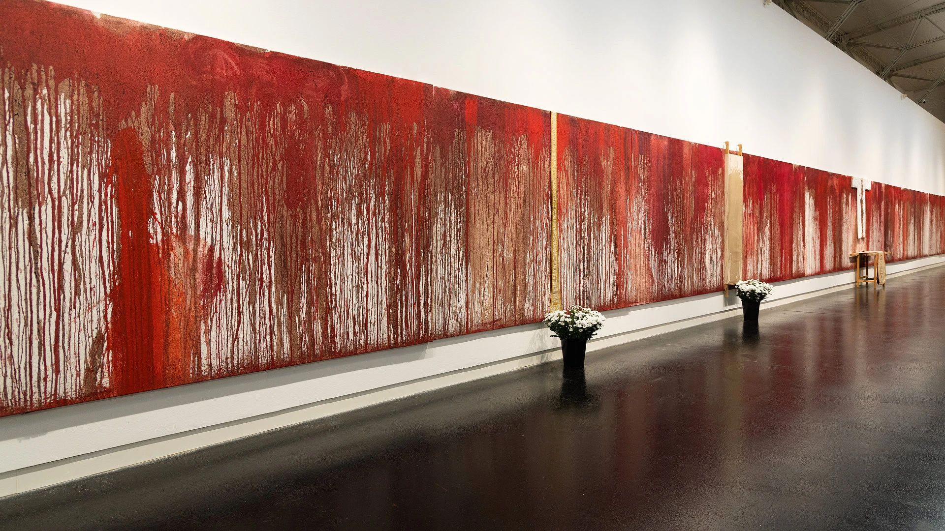 Großflächiges, rotes abstraktes Gemälde mit tropfender Farbstruktur an einer weißen Galeriewand.
