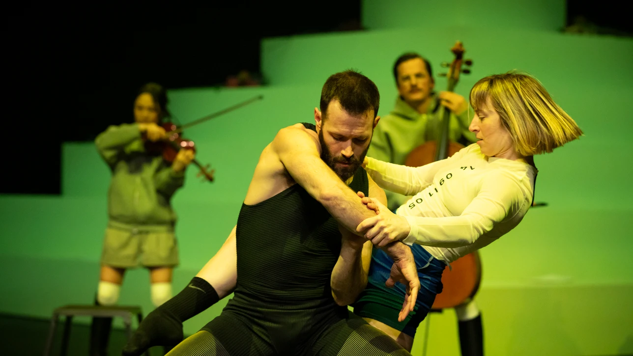 Tanzperformance des Solistenensembles Kaleidoskop unter Leitung von Adam Linder, mehrere Tänzer in dynamischer Bewegung auf einer Bühne.