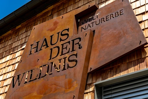 Logo aus Metall in rostiger Farbe auf der Außenfassade des Haus der Wildnis. 