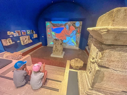 Mithrasgrotte im AMC, zwei Kinder sehen sich das Mithras Relief an 