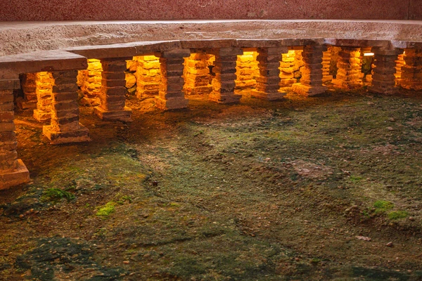 Reconstructed hypocaust heating system in the thermal baths in the Roman quarter, brick turrets illuminated, green moss in the foreground 