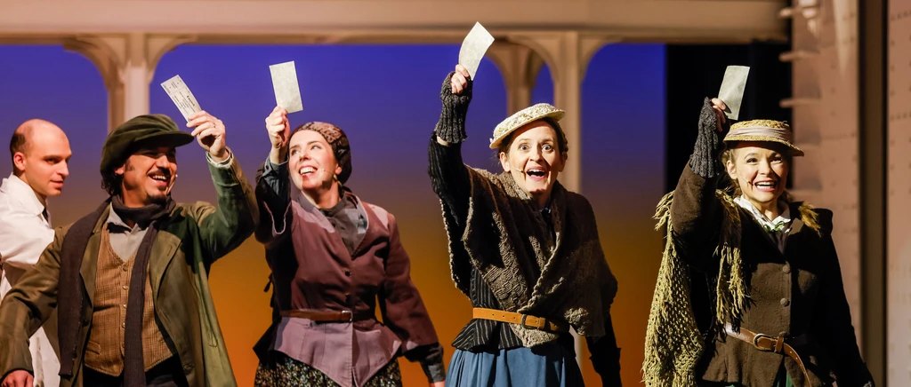 drei Frauen mit Rock und Hut und ein Mann winken mit ihrem Ticket in der Luft, Im Hintergrund ein Mann in weiß und Säulen