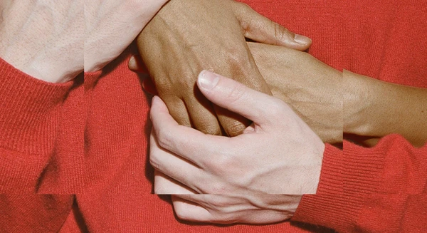The theme for the Festspielhaus’s 2026/2027 season. The design features hands touching, a sleeve in a deep red colour against a red background created by the colour of the jumper.