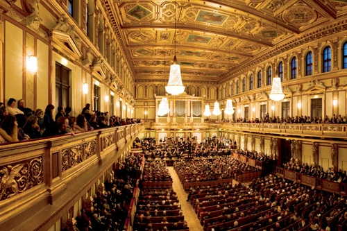 Opulenter Konzertsaal mit reich vergoldeter Decke, großen Kronleuchtern und voll besetztem Publikum.