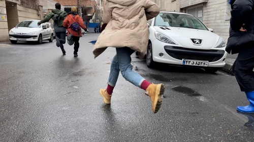 A still from the short film ‘Until’ by Tanin Torabi, showing a dynamic scene of people in an urban setting, seen from behind as they run.