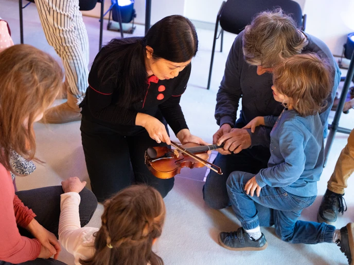 Musikerin zeigt Kindern, wie man über die Geige streicht