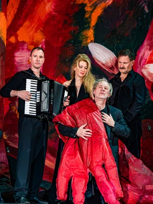 Gruppenbild in rotem Bühnenbild: Joseph, die Sucht (Oliver Urbanski), Therese, die Liebe (Julienne Pfeil), Stefan, das Wunder  (David Oberkogler), vorne: Andreas, der Trinker (Joseph Lorenz);