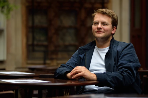 Mann in dunkler Jacke mit Brille am Klavier