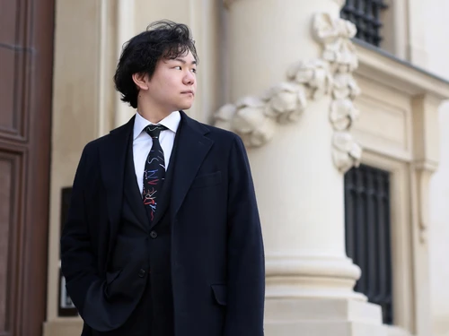 Mann in Seitenansicht mit Anzug und bunter Krawatte vor einem Portal