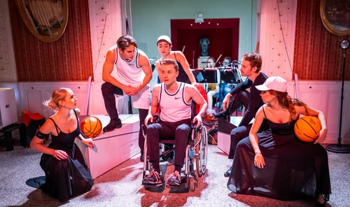 Fünf Personen umrunden eine im Rollstuhl sitzende sechste Person 