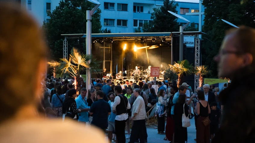 Photo from the “StadtLandFluss” festival, showing the crowd on the festival hall forecourt in the early evening.