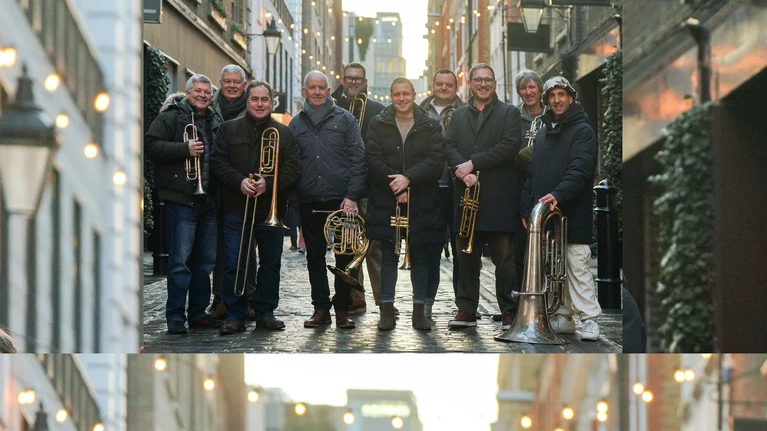 A photo of the London Brass Ensemble with their brass instruments in front of an urban (London) street.