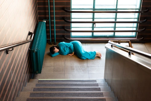 Frau liegend am Boden im Stiegenhaus in der Tabakfabrik Linz
