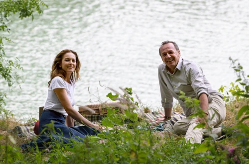 Ein Paar sitzt an einem See auf einer Picknickdecke im Grünen