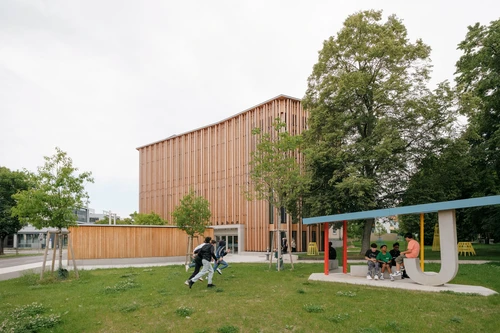 Kinder spielen im Altoonapark. Im Hintergrund sieht man den Holzbau des KinderKunstLabor.